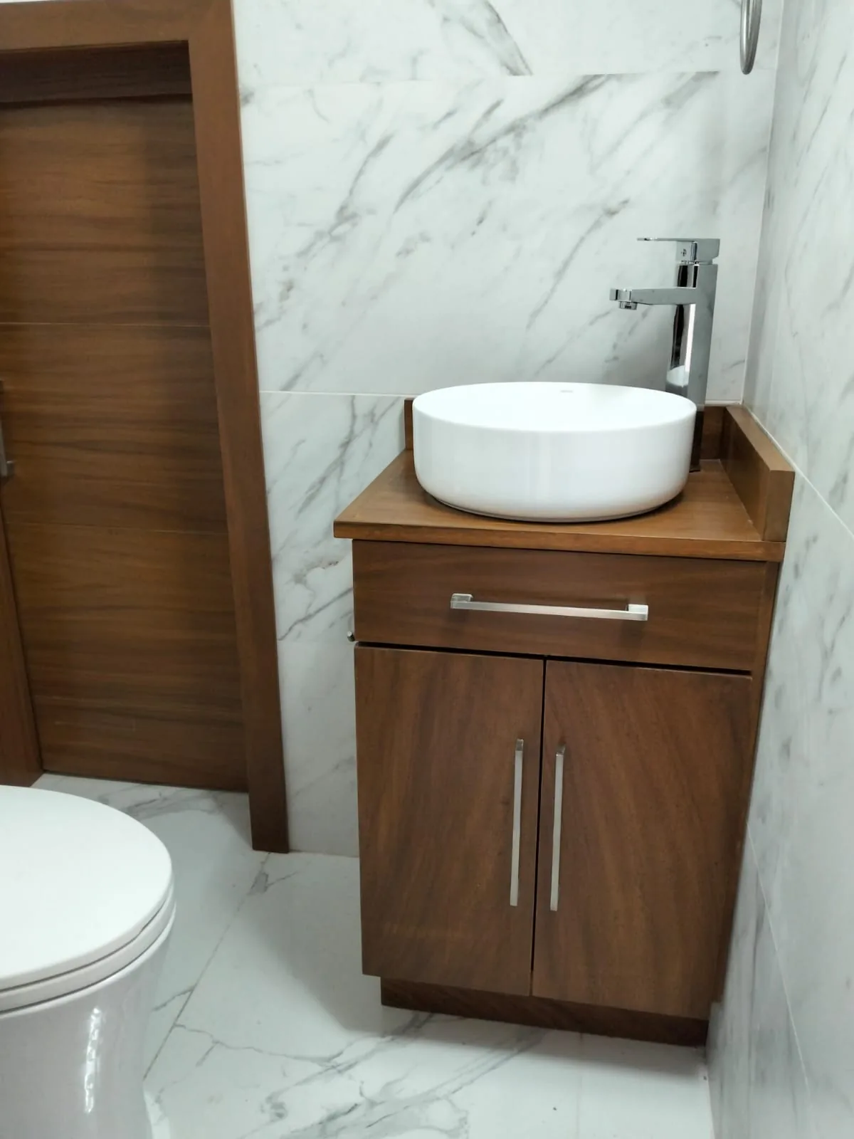 Baño remodelado con madera y superficies tipo mármol