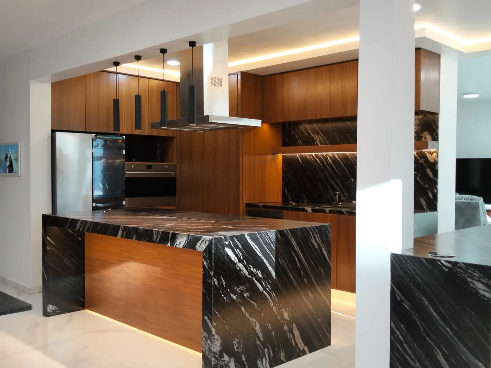 Cocina con isla de piedra oscura, carpintería y luz indirecta