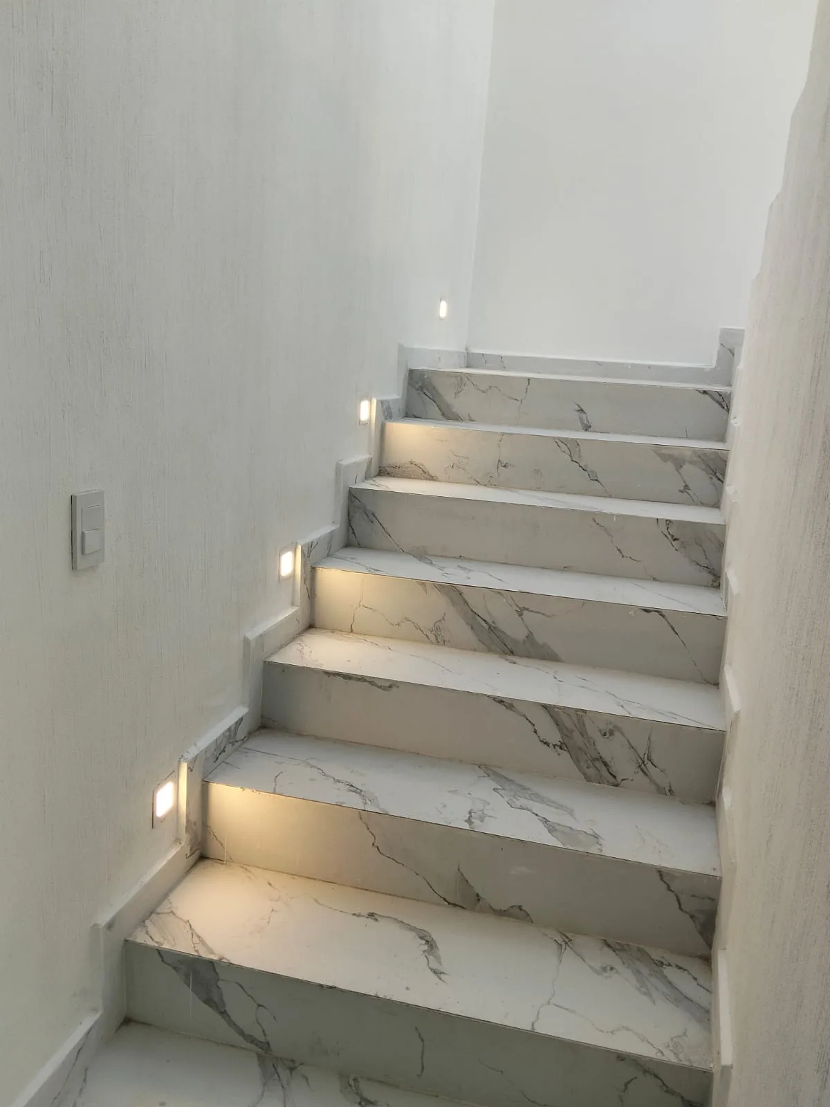 Escalera clara con vetas y luces de cortesía