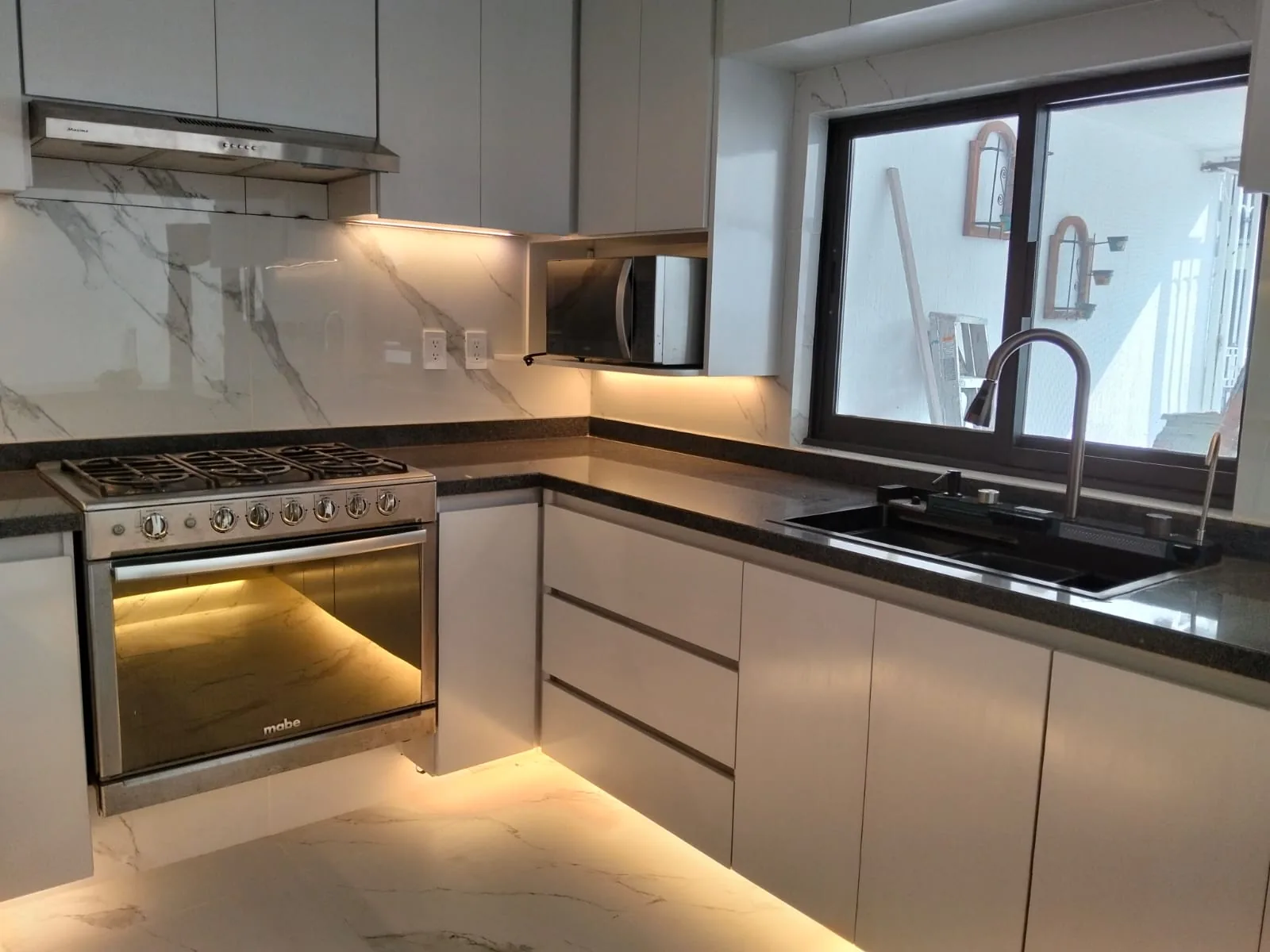 Cocina con muebles grises, cubierta oscura e iluminación lineal