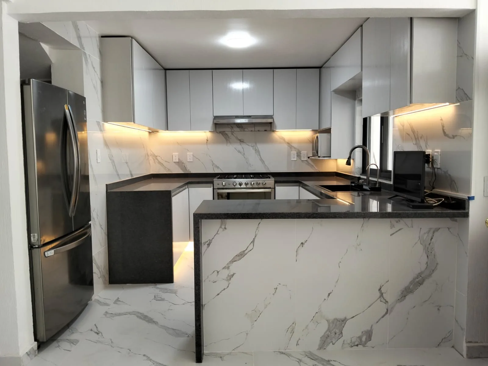 Cocina blanca y gris con península y cubierta de piedra